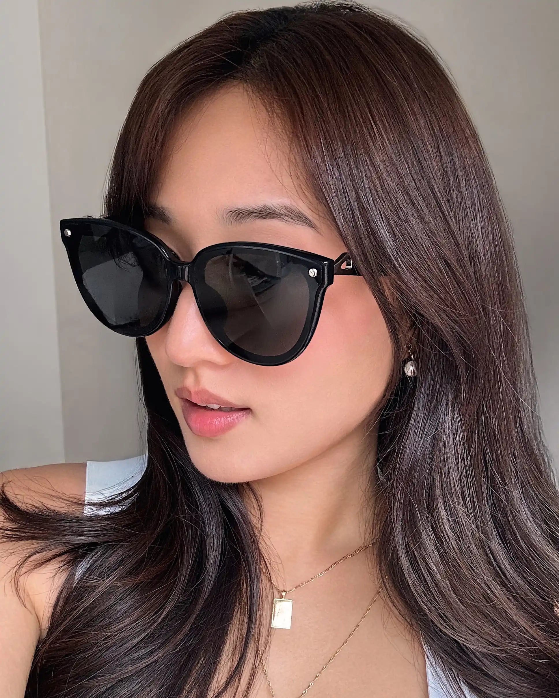 Woman wearing Sweet Pain NANA G1 sunglasses in glossy black, indoor selfie